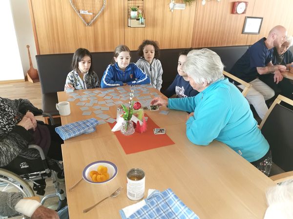 Kinder spielen Memory mit älteren Menschen